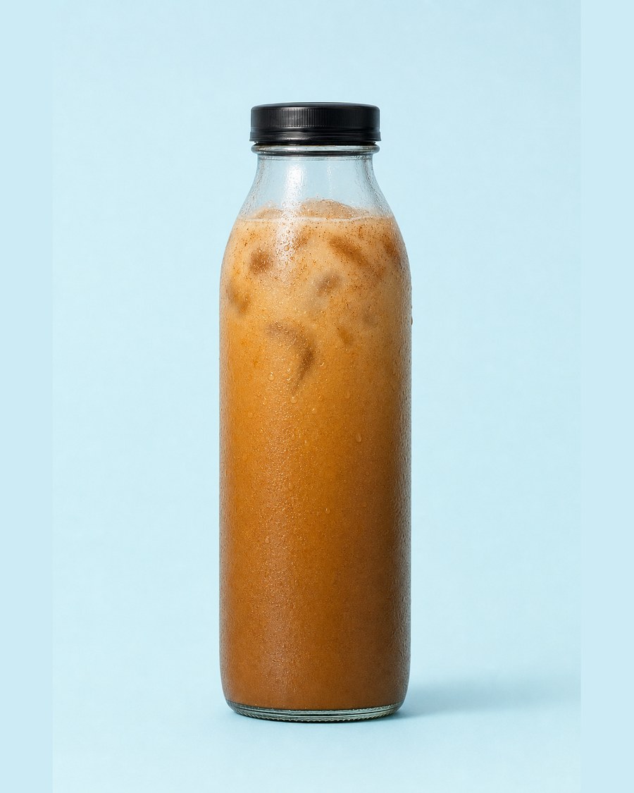 Pumpkin Spice Latte in a clear 12 oz glass bottle on a pale blue background